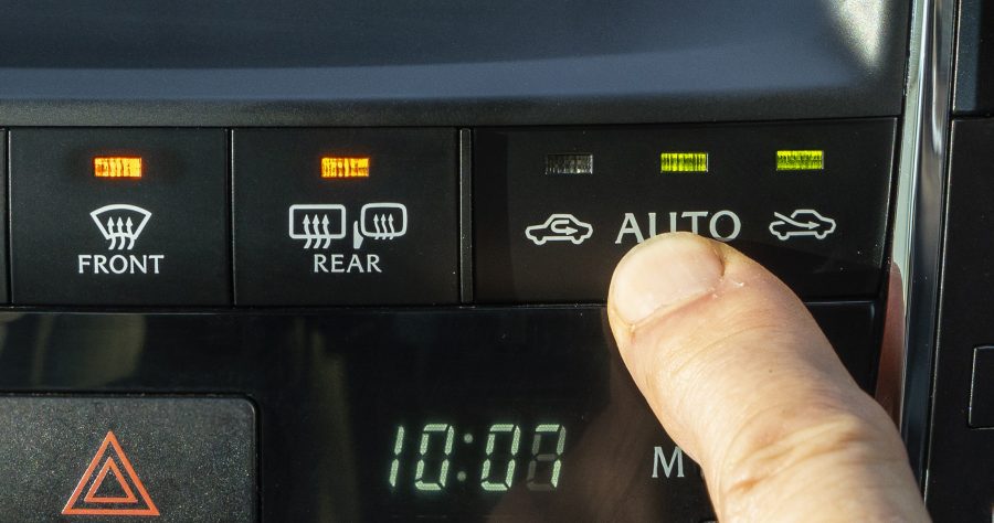 A man's finger presses the heating controls in a Lexus.