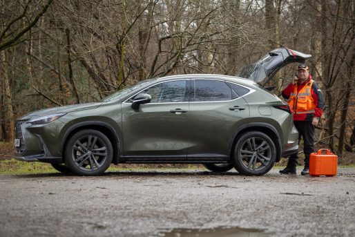 Lexus NX450h+ Plug-In Hybrid Electric Vehicle in a forest with a man in search and rescue gear from afar